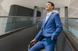 © Minerva Studio - Confident businessman riding on escalator