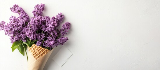 Fototapete - Flower arrangement Lilac in a waffle cone alongside a kraft paper postcard on a white background Flat lay top view copy space Represents proposal gratitude tenderness and love