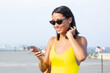 © BullRun - Good looking hipster girl in trendy fox glasses for sun protection using cellphone device for virtual messaging with web friends from social networks, happy woman smiling while watching mobile video