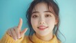 © yj - Happy young Korean model pointing at copy space isolated on light blue background. Smiling Asian American woman looking at camera, advertising promo, presenting ads shopping offer.