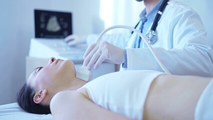 Wall Mural - Doctor man with white medical gloves is using ultrasound machine to examine neck of female patient lying down in clinic. Medicine concept