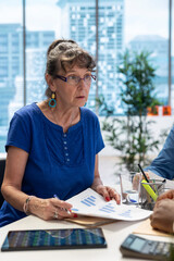 Elderly couple in a modern office setting discussing retirement plans with a financial advisor, looking into various options. Covering savings strategy and family expenses with investments.