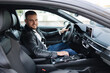 © Aleksandr - Success in motion. Handsome young man in leather jacket smiling while driving a car. Side view from inside