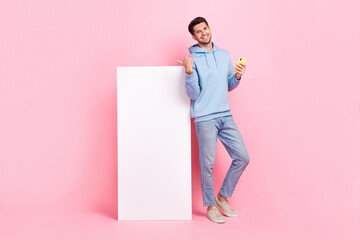 Poster - Full body length photo of positive guy entrepreneur hold smartphone eshop finger point smartphone website isolated on pink color background