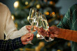 © Seventyfour - Cropped shot of unrecognizable people clinking glasses with champagne celebrating Christmas together at festive dinner, cope space