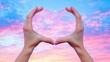 © Spear - Capturing Love in Nature: A Heart Shape Formed by Hands Against a Colorful Sunset Sky