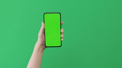 Young woman hand show smartphone with green screen on green background