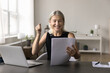 © fizkes - Excited happy mid aged business lady entrepreneur freelancer read paper notification with loan mortgage approval from bank. Older age woman small company owner overjoyed with financial report result