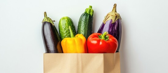 Fototapete - Healthy vegetables including eggplant tomato pepper and cucumber in a paper bag against a white background. with copy space image. Place for adding text or design