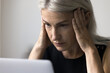 © fizkes - Close up shot worried elderly female worker employee freelancer look on laptop screen rub temples in panic mess confused with bad news in email message. Troubled old lady has serious business problems