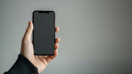 Poster - A hand holding a black smartphone with a blank screen, against a plain grey background.