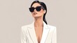 © vefimov - Woman wearing sunglasses and a white jacket. She is standing in front of a gray background. Concept of elegance and sophistication