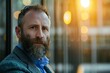 © Odin AI - A bearded man in business clothes looks thoughtfully into the distance as the warm sunset light illuminates the modern urban backdrop, indicating reflection and maturity.