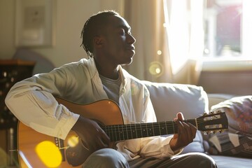 An individual is immersed in playing guitar as warm sunlight bathes him, expressing tranquility and a deep connection with music in a serene morning setting.