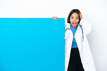 Wall Mural - Young mixed race doctor woman with a big placard isolated on white background surprised and pointing finger to the side