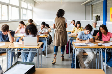 Diverse young group of high school students doing an exam at classroom. Education lifestyle and back to school concept.