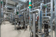 © alhim - A complex network of pipes and valves is illuminated in a well-lit industrial space. Pumps and gauges are strategically arranged, emphasizing functionality and design..