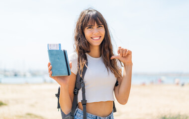 Young woman holding a passport at outdoors proud and self-satisfied