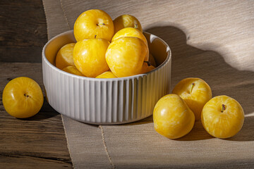 Wall Mural - ripe sweet yellow plums in a ceramic bowl on a wooden table