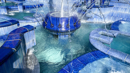 Vibrant blue-tiled water fountain with cascading streams, symbolizing relaxation and tranquility, perfect for summer vacation or urban decoration themes