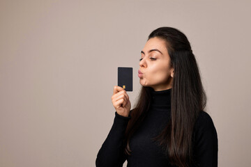 smiling happy woman wears black shirt holding in hand mock up of credit bank card. copy space, cashless lifestyle