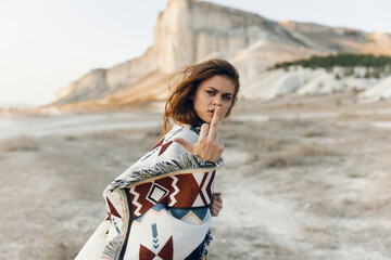 Wall Mural - Mysterious woman standing in front of majestic mountain, hand on mouth