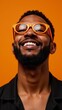 © Pixel Matrix - A bearded black man with orange glasses grins at the camera against an energetic orange backdrop