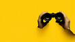 © deimos.az - A hand holding binoculars is peeking through a hole in a yellow paper banner with a copy space area