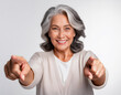 © theshooter - Mujer mayor sonriente señalando al frente con las dos manos aislada en fondo blanco