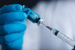 © Alernon77 - A blue-gloved medic's hand holds a syringe and test vaccine