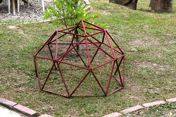 Red metal dome-shaped structure on grass in a playground setting.