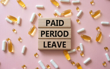 Paid Period Leave symbol. Concept words Paid Period Leave on wooden blocks. Beautiful pink background with pills. Healthcare and Paid Period Leave concept. Copy space.