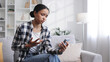 © YURII MASLAK - Worried young African American girl sitting on the sofa looking