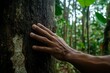 © JAYDESIGNZ - Hand touching tree trunk in forest promoting environmental care