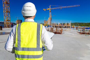 Poster - man builder stands back to camera. inspector checks safety precautions during construction. foreman 