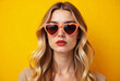 © DariaTrofimova - Portrait of a young blonde girl in heart-shaped glasses on a yellow background