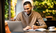 © Prostock-studio - Inspired afro manager working in cafe, using laptop and taking notes in his organizer, empty space
