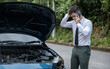© sorapop - Man driver waiting for towing service after car accident on road. businessman in suit standing on highway, talking on telephone with displeased expression. Concept insurance and transportation.