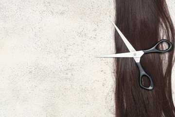 Wall Mural - Brunette hair strand for donation with scissors on beige grunge background