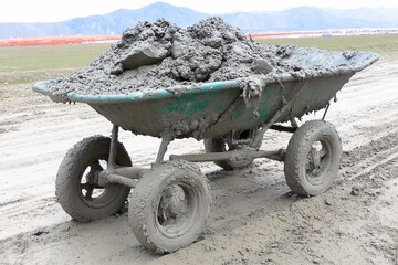 Wheelbarrow Filled with Concrete on Dirt Road Construction Site