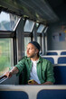 © DimaBerlin - Thoughtful man riding public transportation, looks out window with interest, enjoys calm trip with music in headphones using phone. Focused male tourist travel by electric train reflection about life