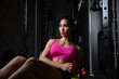 © kamonrat - Focused Woman Exercising on Gym Equipment with Determination, Wearing a Pink Sports Bra, Strengthening Core Muscles, Fitness Training for Endurance and Healthy Lifestyle in a Dark Gym Setting