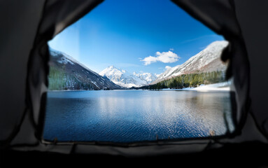 Poster - A view of a calm lake and snow-capped mountains seen from inside a tent.