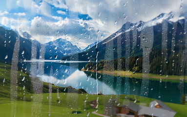 Poster - A view of a mountain lake and snow-capped peaks through a rain-streaked window.