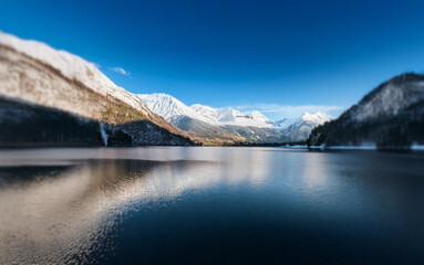 Poster - A still lake reflects snow-capped mountains under a bright blue sky.