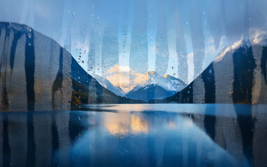 Poster - A misty mountain range reflected in a still lake viewed through a rain-streaked window.