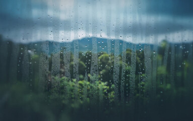 Aufkleber - A view of a misty forest and mountains through a rain-streaked window.