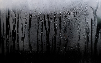 Poster - Water droplets condense on a windowpane, creating a blurry, abstract pattern.