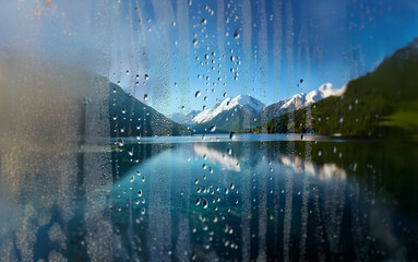 Poster - A view of a mountain lake and snow-capped peaks through a rain-streaked window.