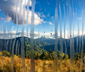 Poster - A view of a mountain range through a condensation covered window.